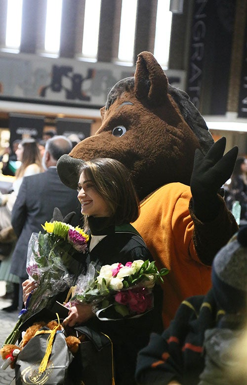 Porcellino mascot and a new grad with armloads of flowers