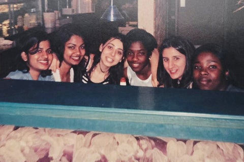Archival photo of six friends huddles around a booth in a busy cafe
