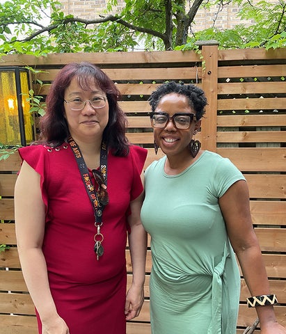 Phoebe and Nadia smile in front of a wooden fence outside