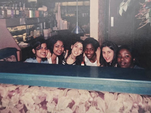 Archival photo of six young women gathered around a booth in a coffee shop