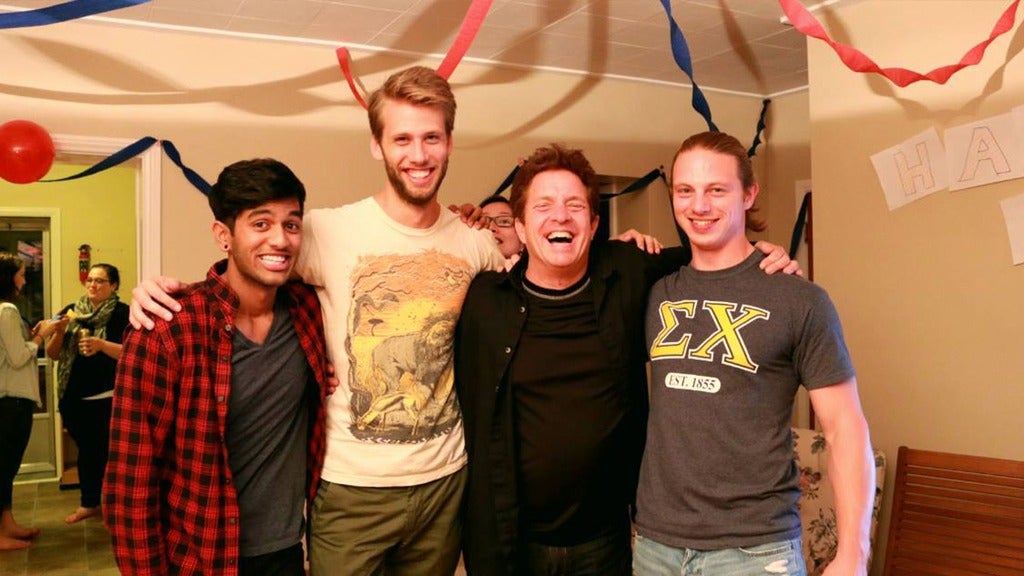 Four friends smile with their arms around each other at a party