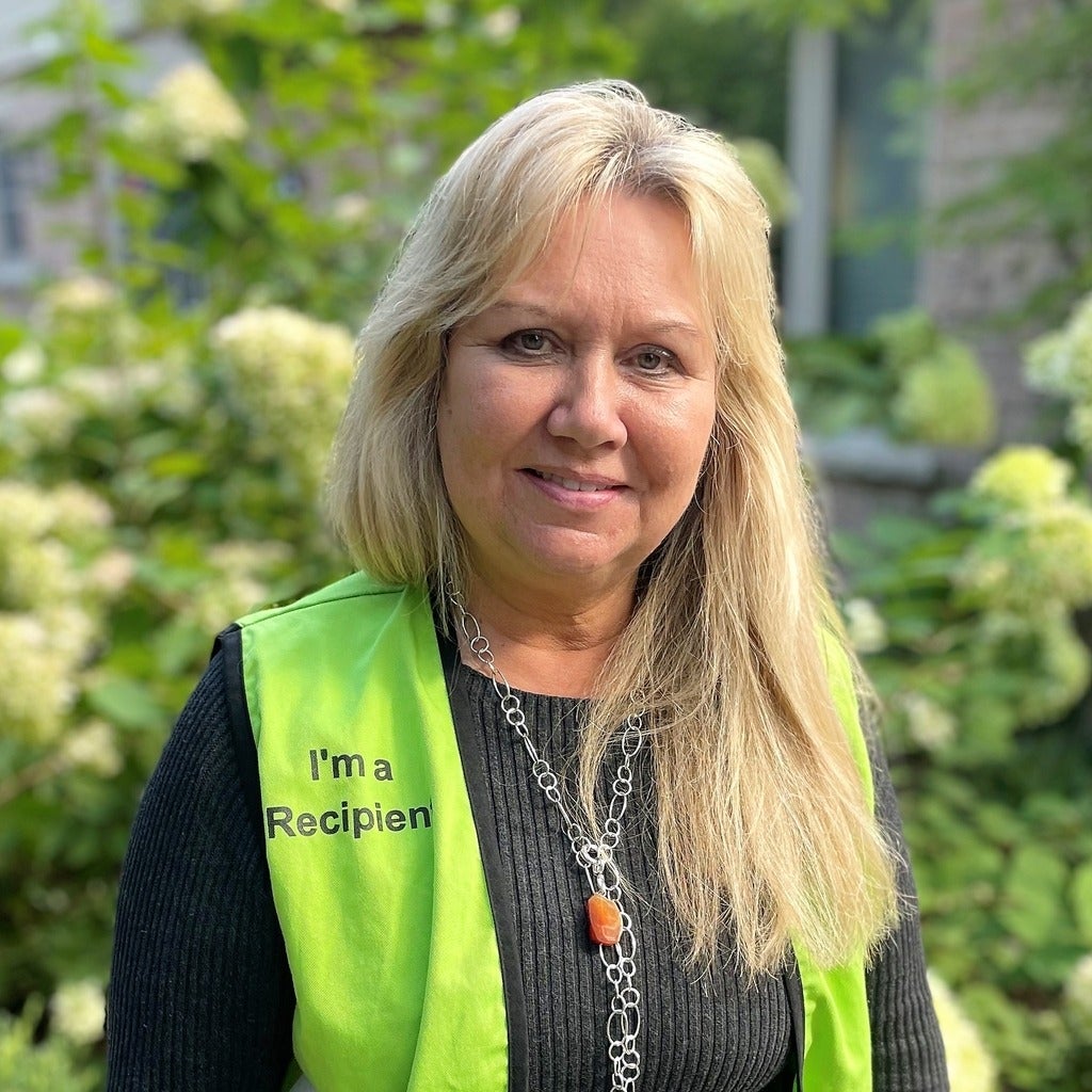 Susan McKenzie wearing high visability vest with I'm a Recipient written on it