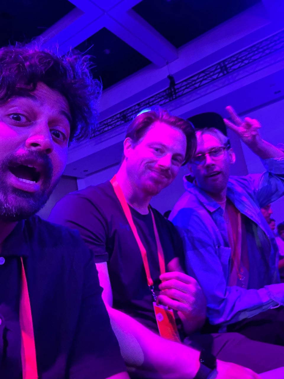 Tyler, Sudar, and Ryan smile in a backlit room