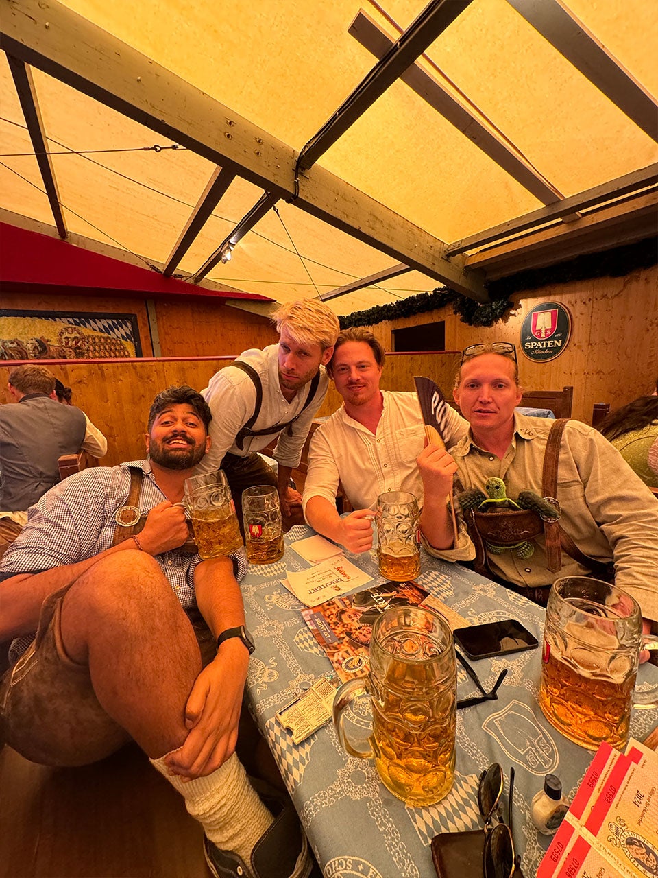 Four friends dressed in suspenders drink in a beer tent