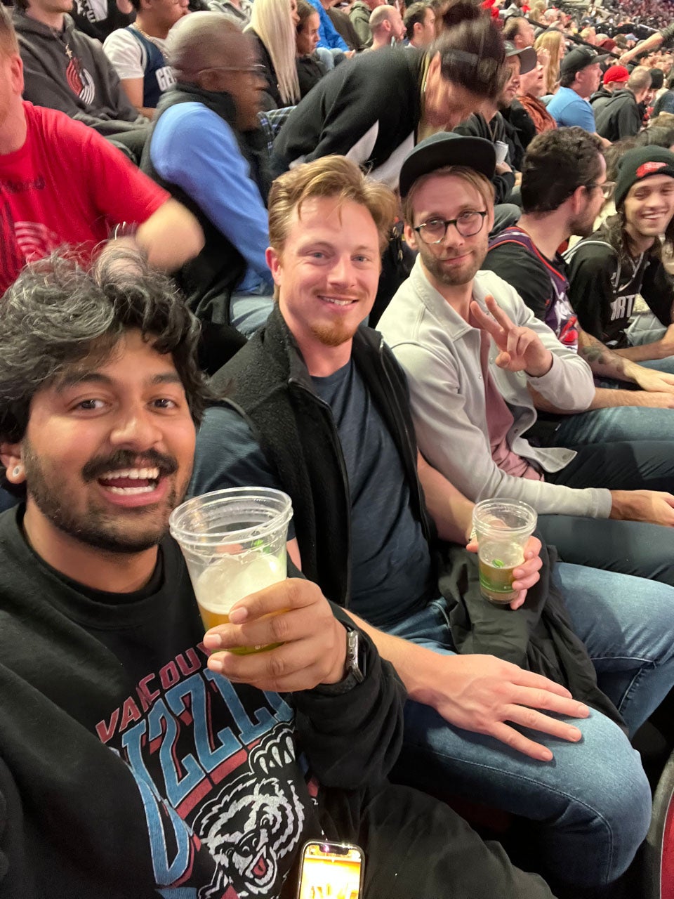 Three friends smile in crowded stands