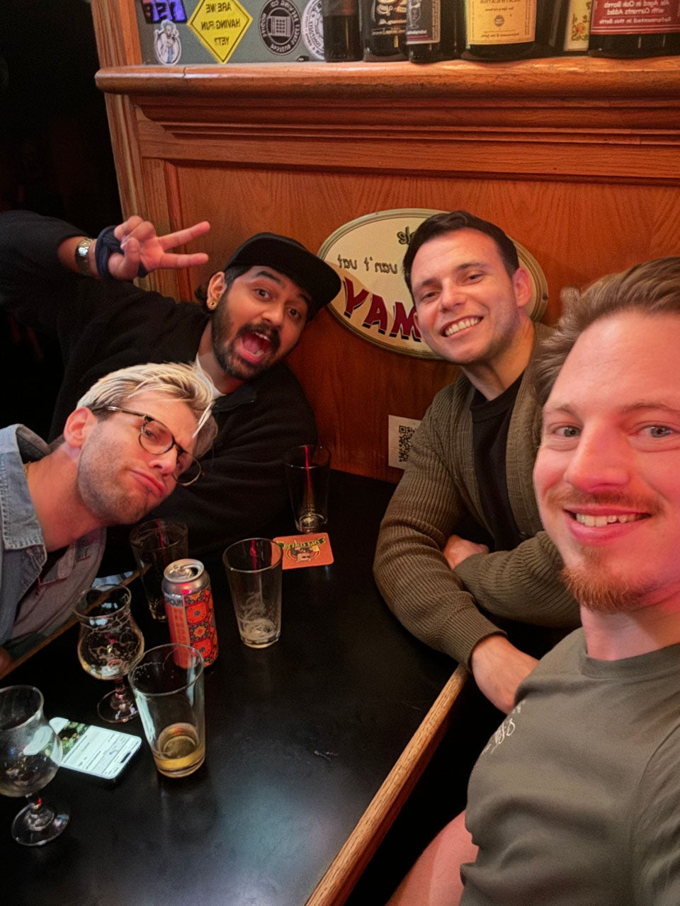 Four friends smile at a booth in a bar