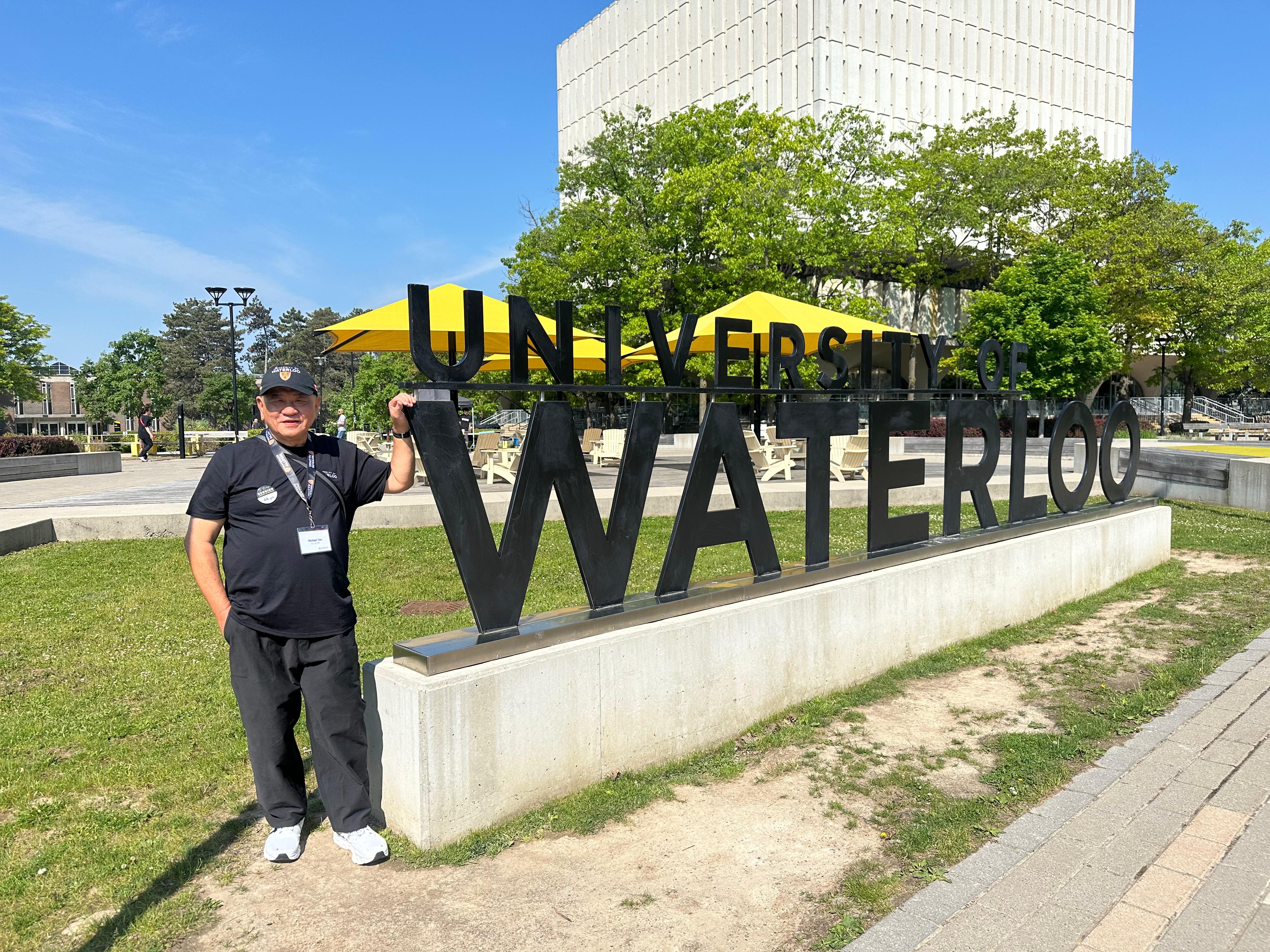 Michael Tee stands beside the UWaterloo sign in front of DP