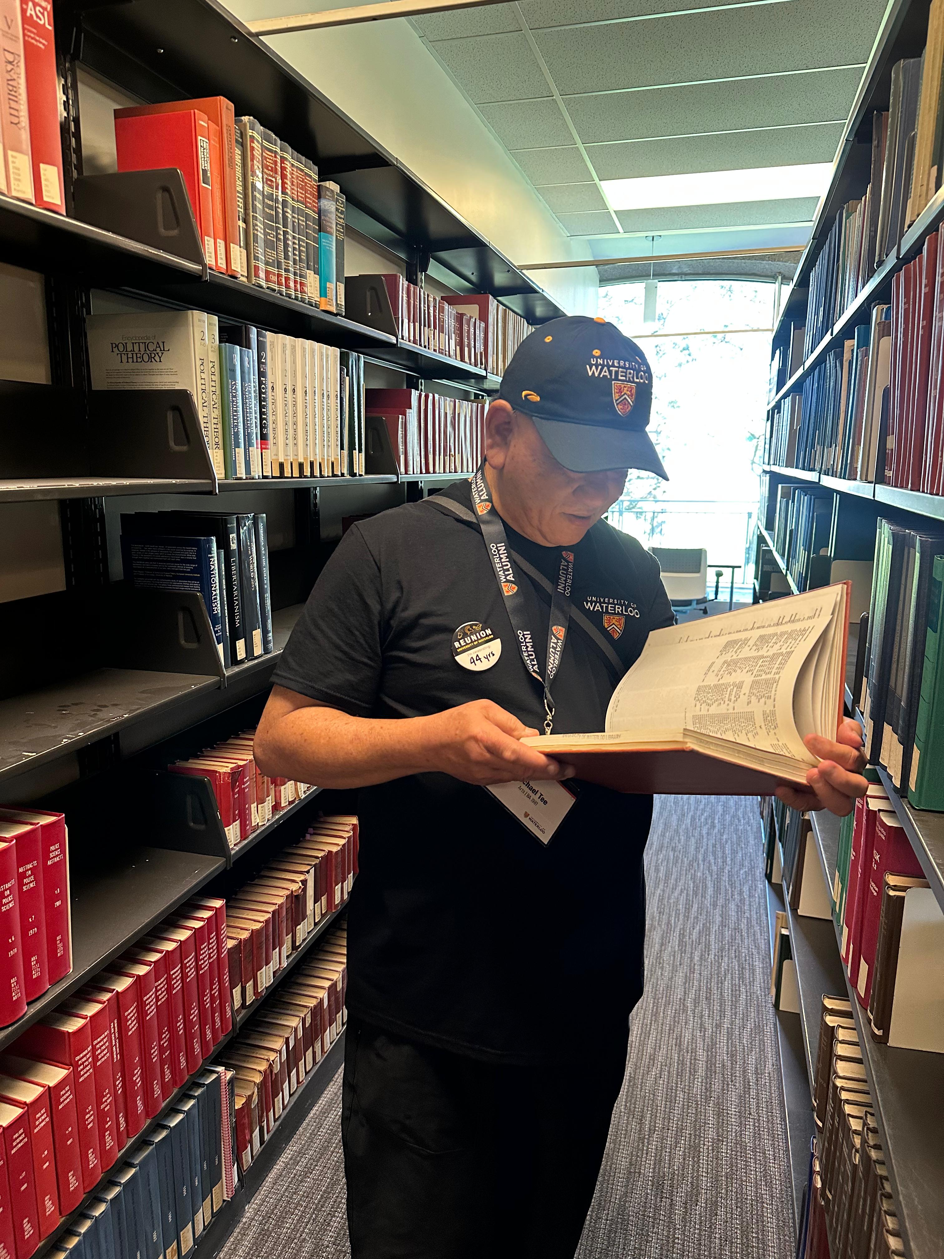 Michael Tee looking through a book in the library