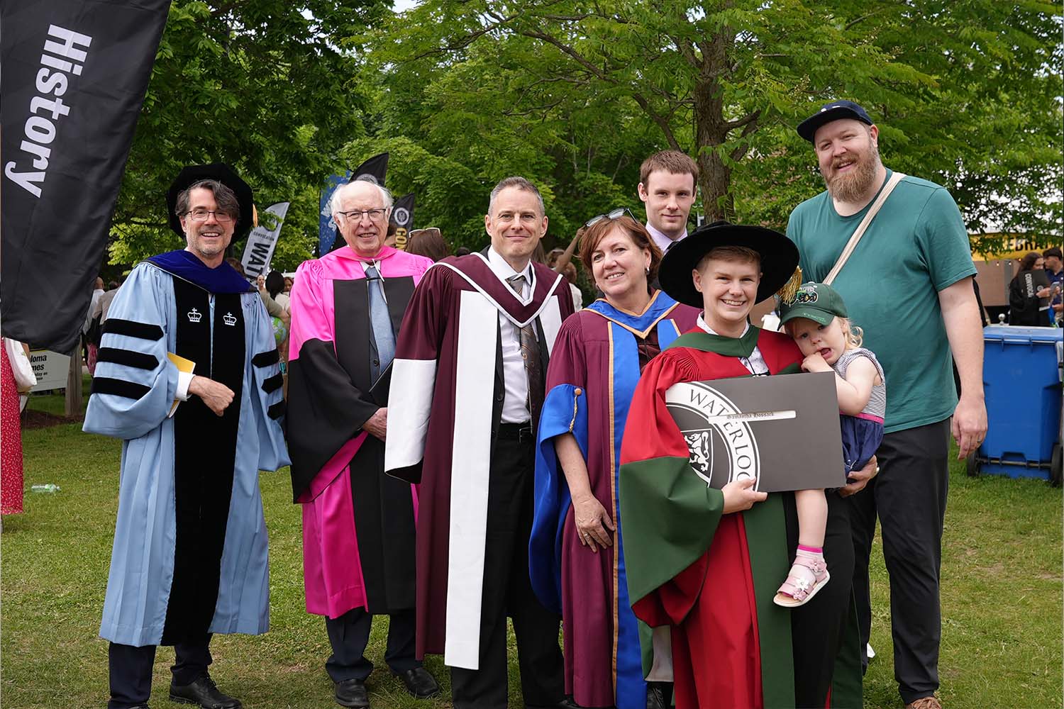 A group of people in formal convocation robes smile
