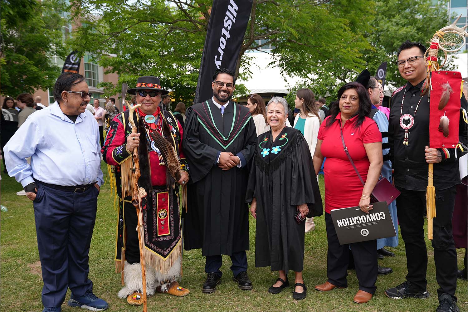 Members from the Office of Indigenous Relations stand with a graduate