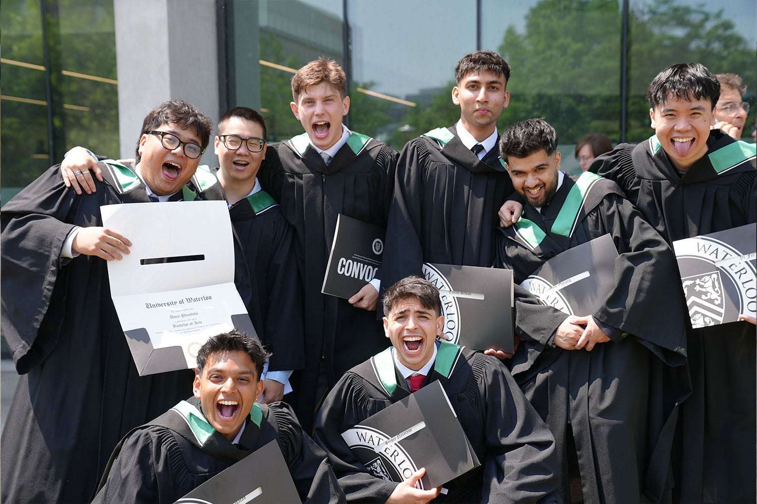 A group of graduates yell excitedly at the camera