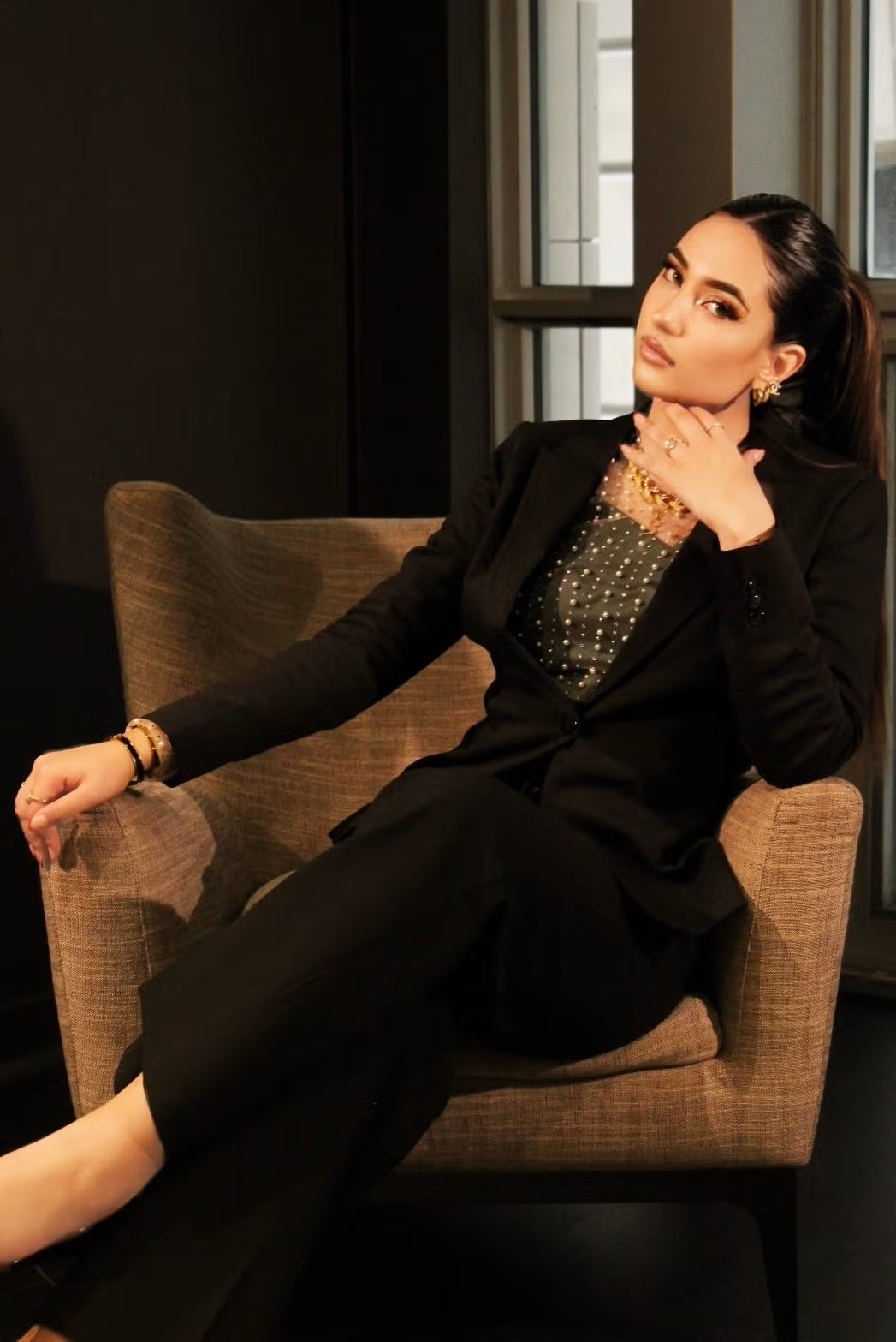 Naimah Venezia looks at the camera leaning on the arm of a chair