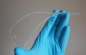 hand with blue latex glove bending a cell phone screen protector 