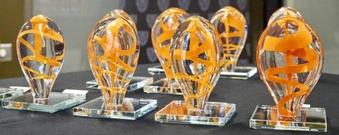 row of glass sculptures with orange swirl in each