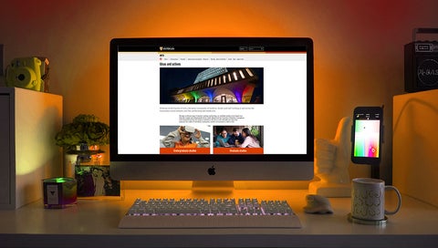 A desktop computer showing the new Arts website homepage is surrounded by an eerie orange glow