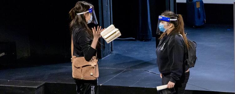 students rehearsing on stage with face masks and shields