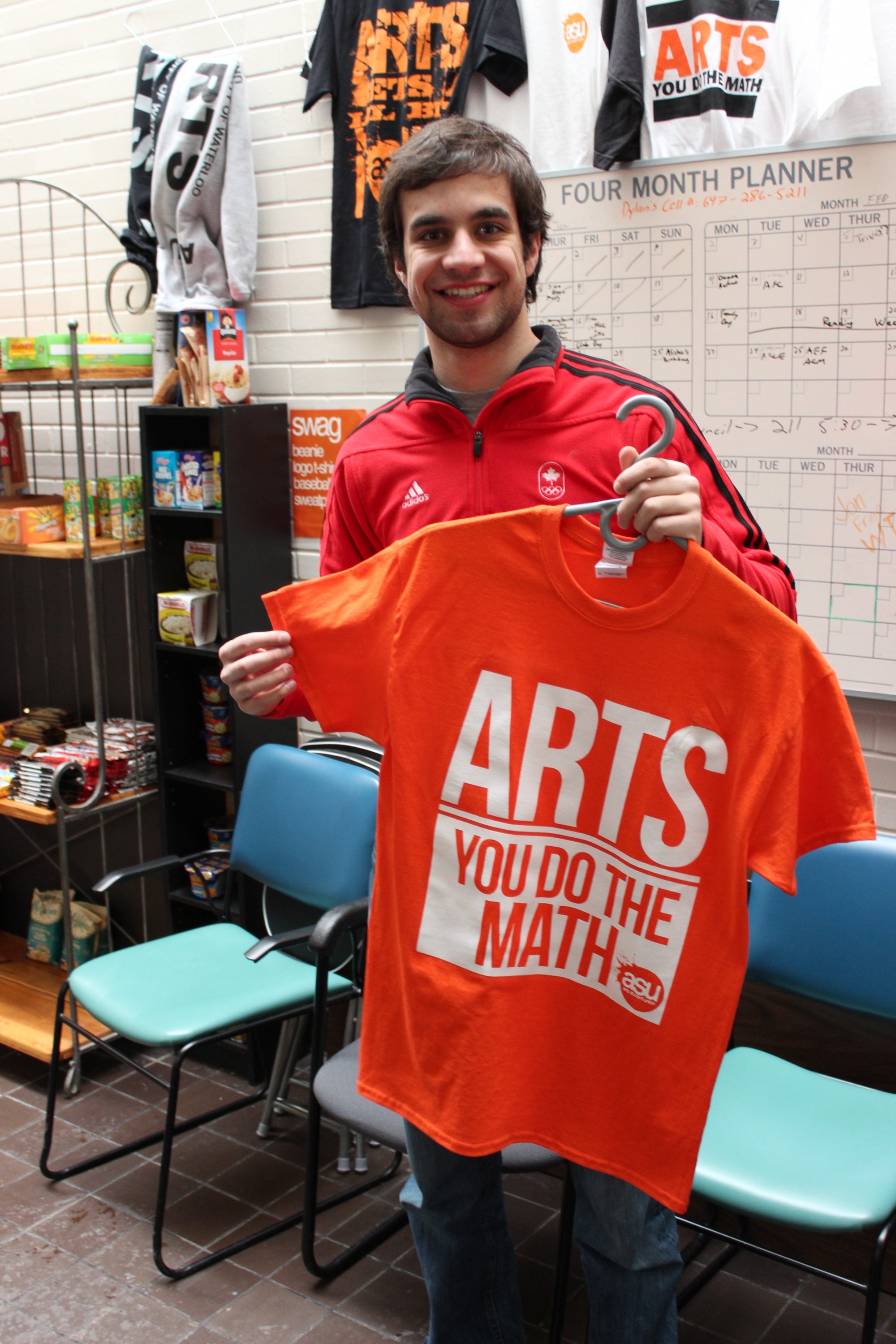 Arts Student Union member holding up an orange shirt.