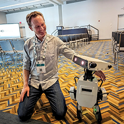 Evan Ackerman with his arm around a small robot