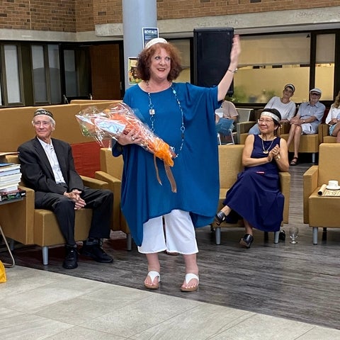 Sheila Ager holding flowers and waving