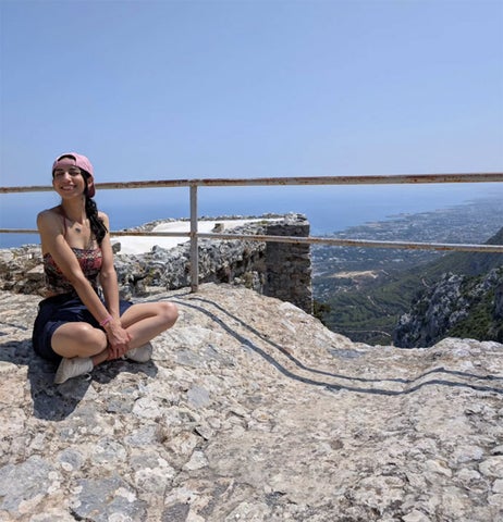 Aicha Lariani near a cliff's edge overlooking the Cypress countryside