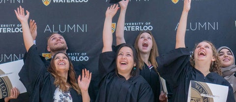 A group of new graduates in their robes toss their hoods in the air in celebration