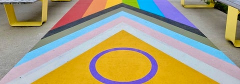 Trans flag with part of Pride flag painted on ground