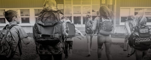 kids with backpacks walking into school