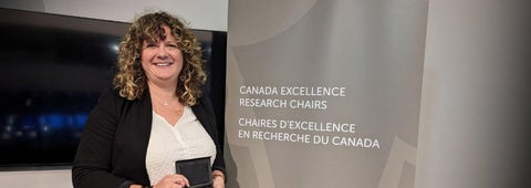 Sara A. Hart poses next to the Canada Research Excellence Chair sign at the awards reception