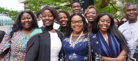 Family and friends smiling around a graduate in robe and hood