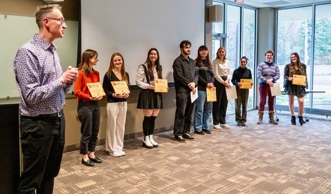 row of nine students and professor in a row with certificates