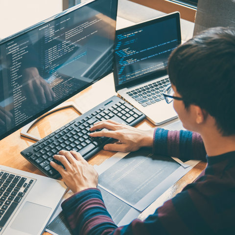  a person working on a computer with three screens of data 