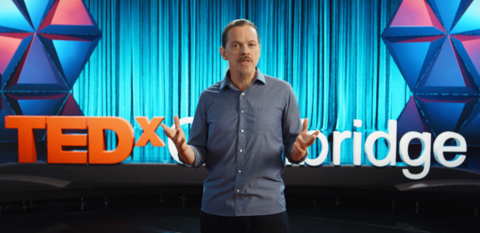 Video still of James Danckert speaking with TEDx Cambridge logo in background