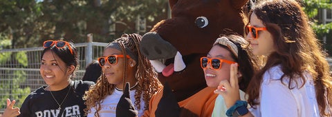 Four students with orange sunglasses stand with Porcellino at Orientation