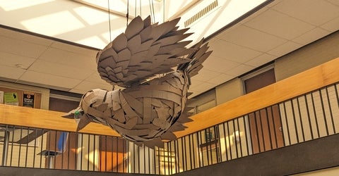 cardboard bird suspended with 2nd floor railing surrounding