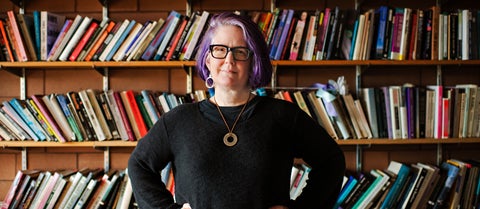 Jennifer Saul stands in front of shelves of books in the philosophy reading room