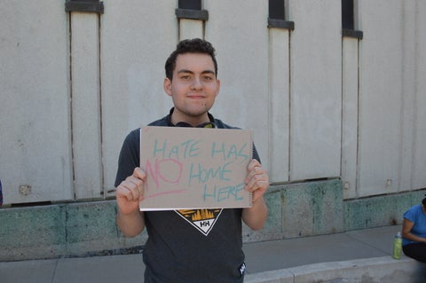 Male student holding sign that says 'Hate has no home here'