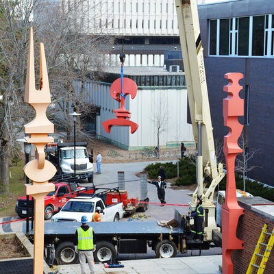 A crane lifts one of the four sculptures