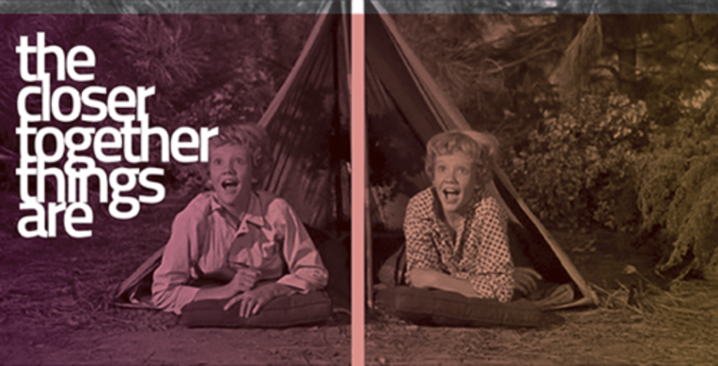 exhibition image showing film still of twins in a tent