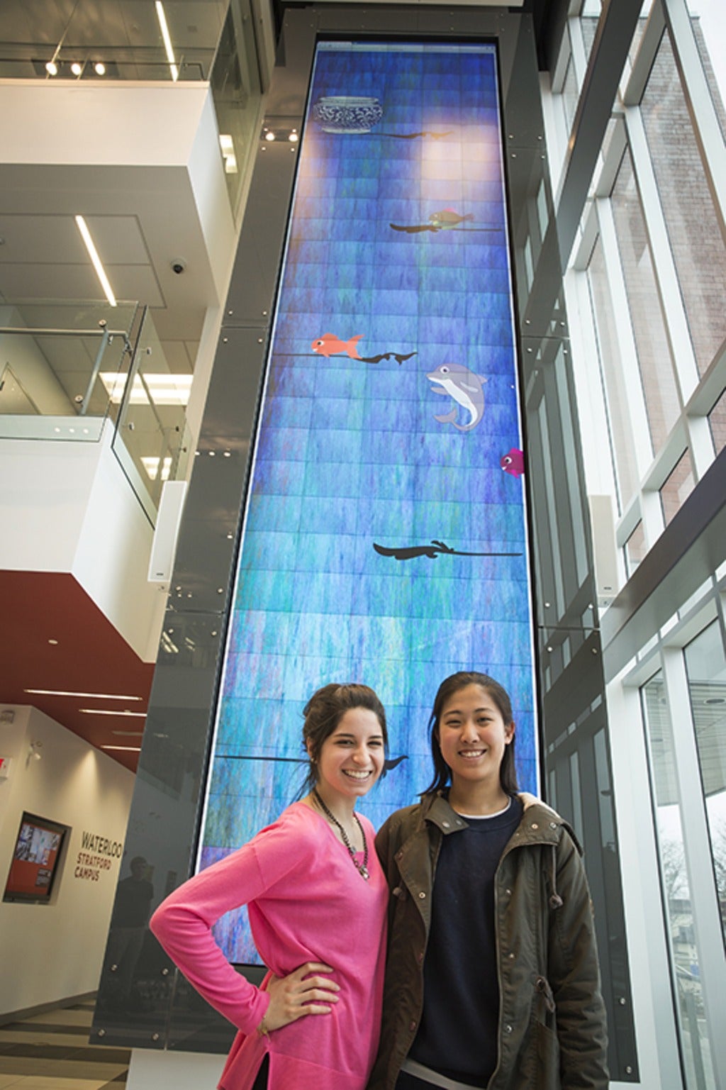 two students stand in front of digital wall