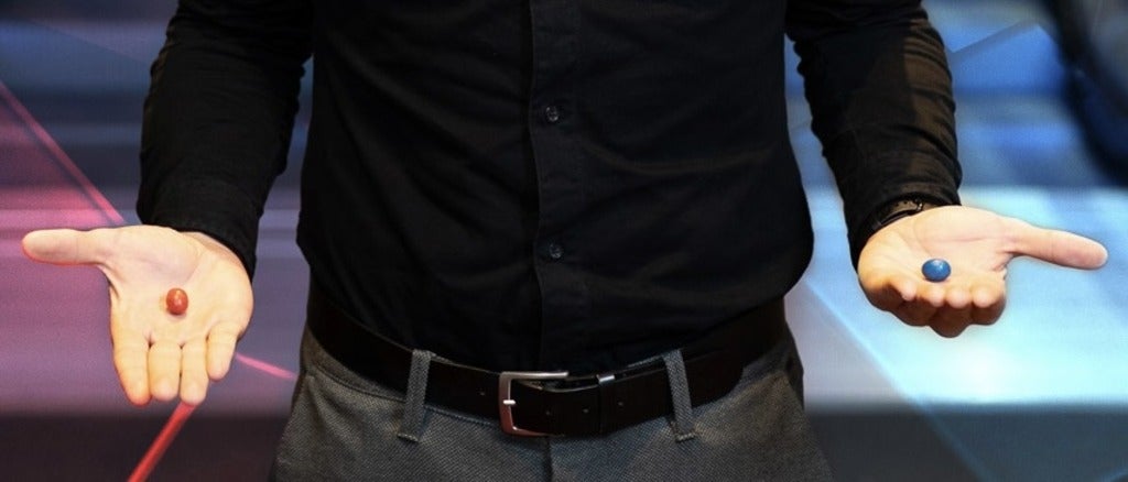 person's hands holding red and blue pills