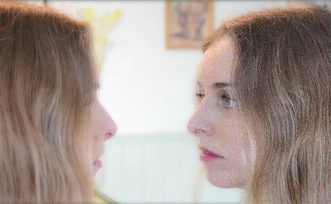 Video still showing a woman looking at a pixelated version of herself in a mirror