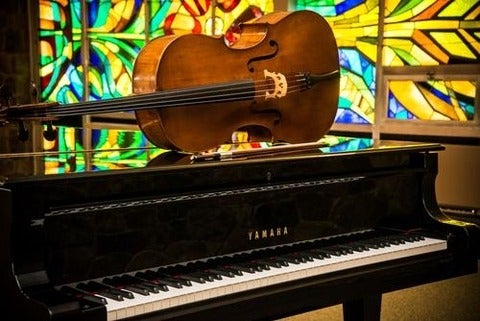 A cello resting on top of a grand piano