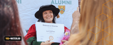 PhD graduate smiling with diploma with You + Waterloo branding