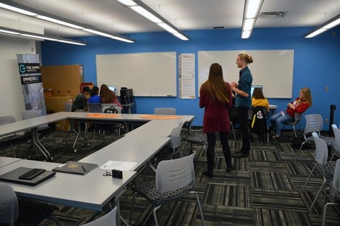 Facilitators standing while students work on computers