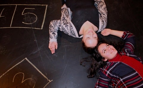two actors lying on stage with chalked numbers