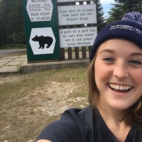 Rachel smiles in front of signs for bears and watershed 