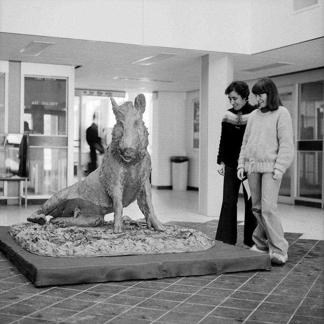 Black and white photo of two students looking at Porcellino's statue in the ML lobby