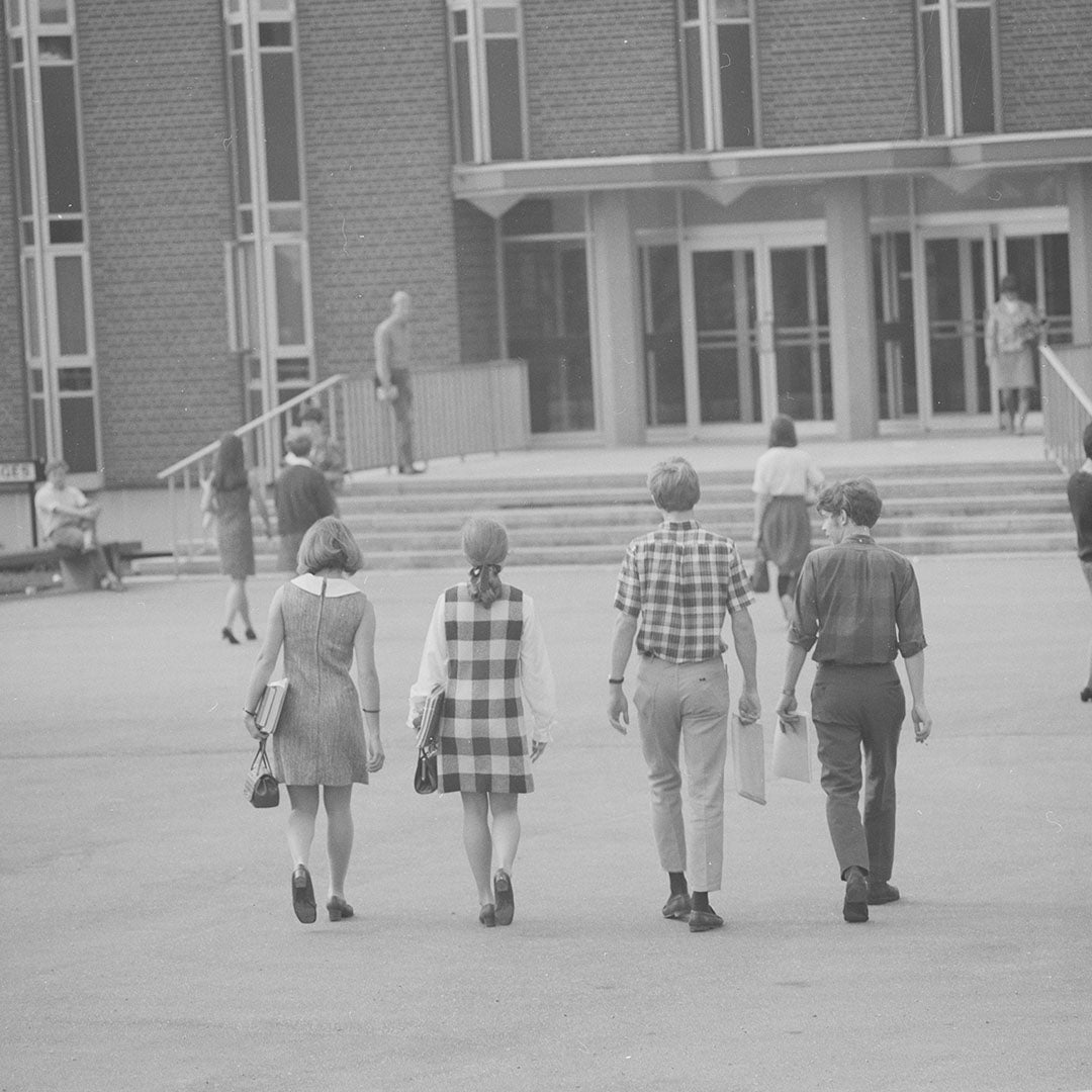 Black and white photo of a group of four students walking toward ML