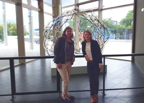 Myra Fernandes and colleague in front of sculpture of brain