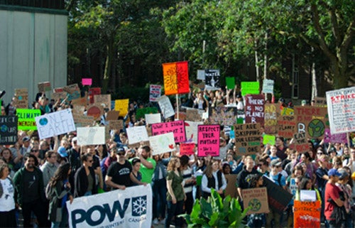 Students, staff and faculty pack the Arts Quad for a climate change protest. Some are holding sign with climate change slogans on them.